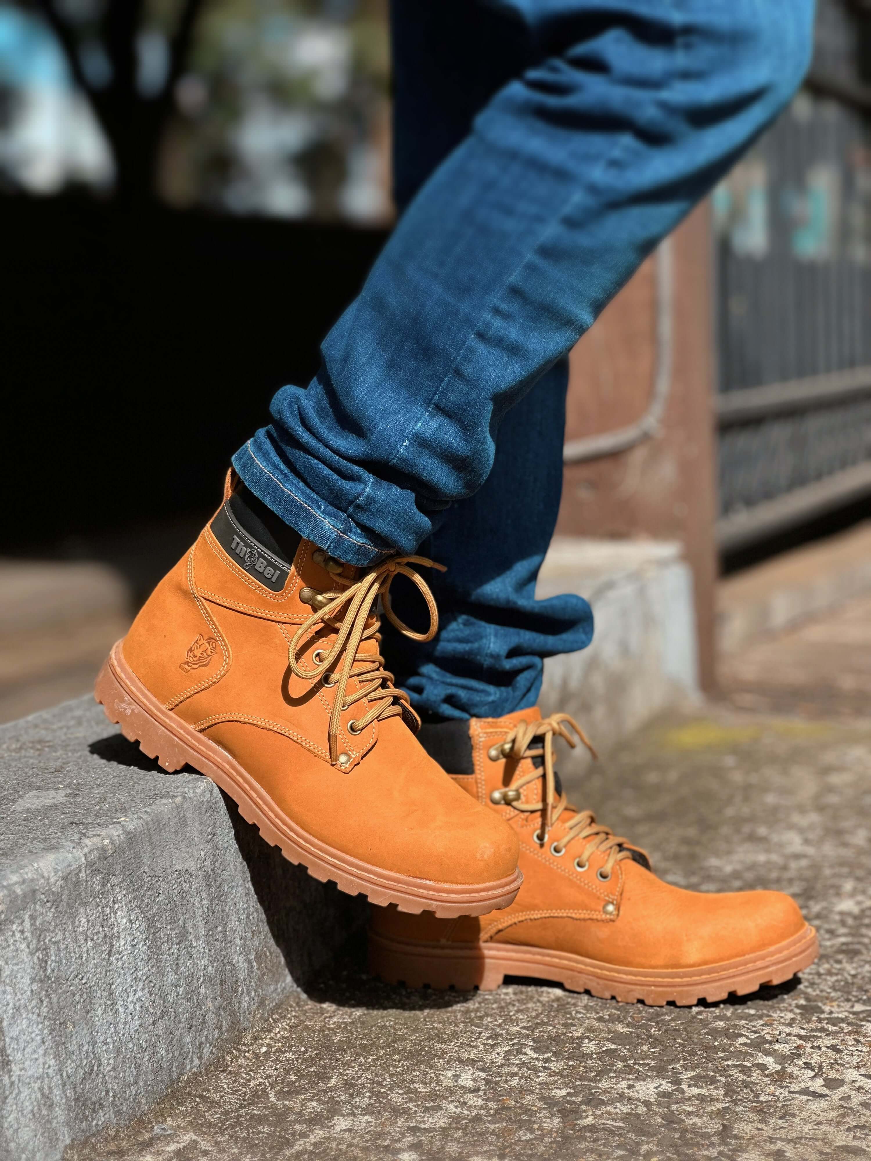 Botina masculina: conforto, estilo e funcionalidade, destacada em jeans e uma bota robusta, caminhando ao ar livre.