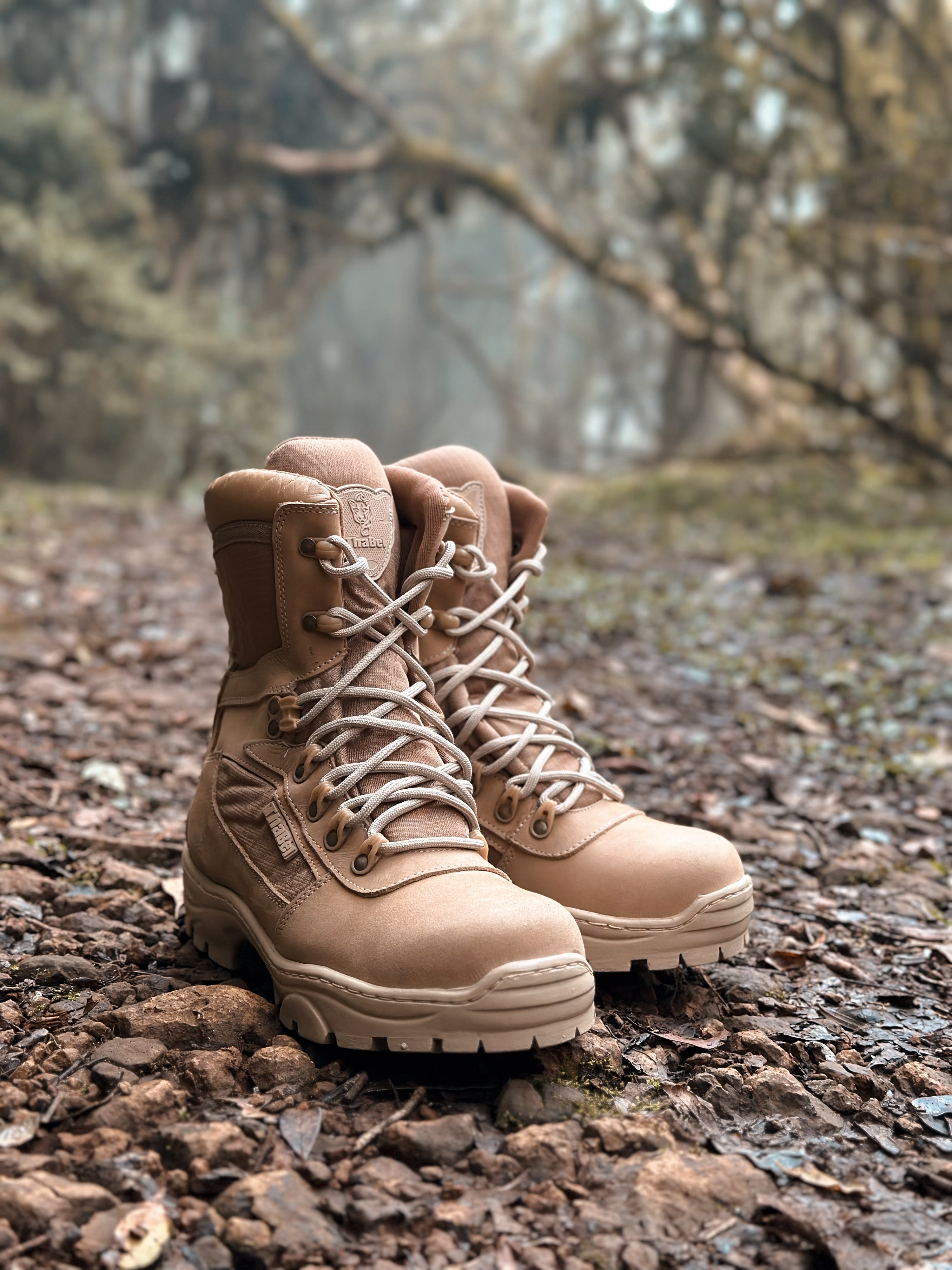 Botas coturno militar em um caminho de terra com vegetação ao fundo.