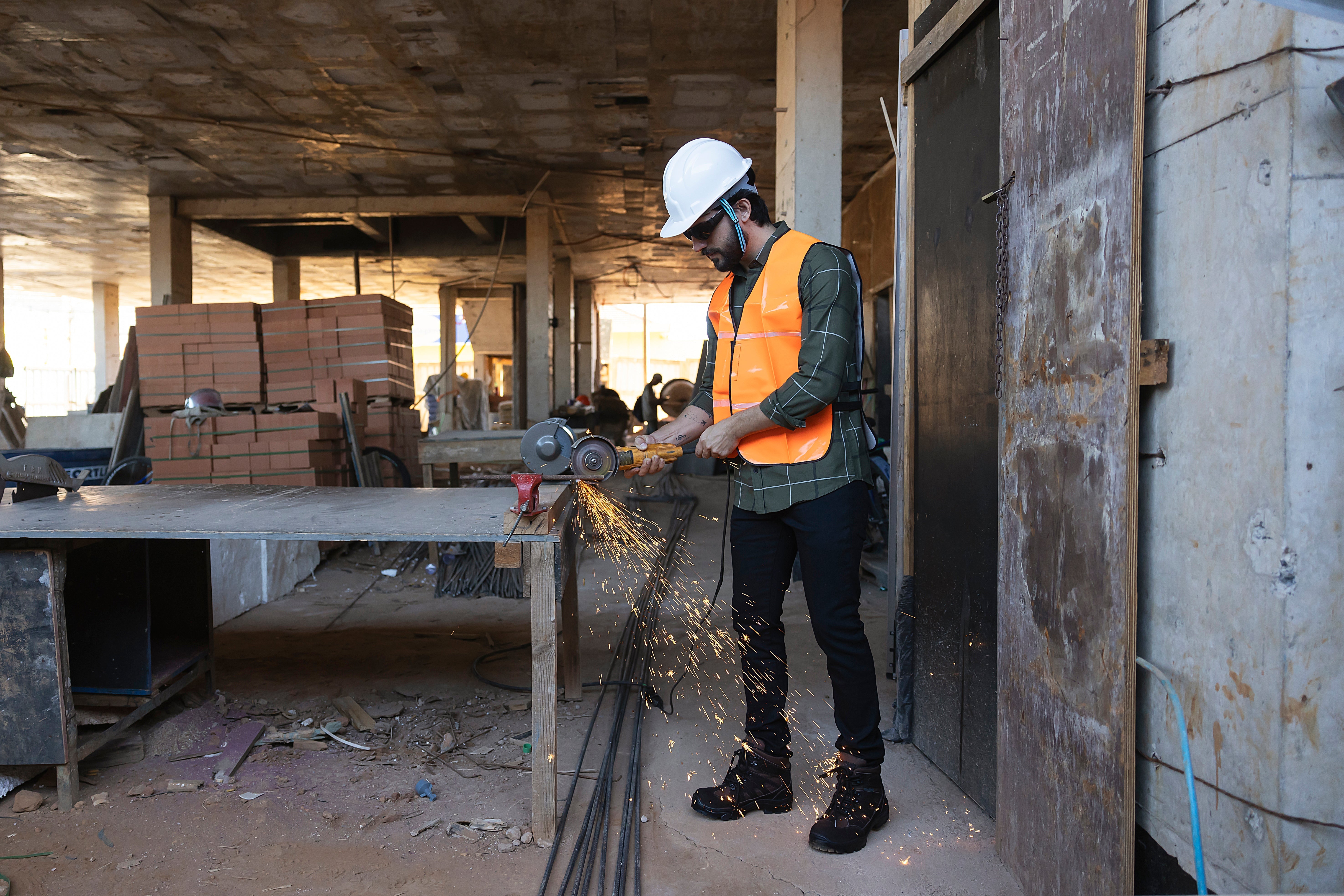 Homem operando uma ferramenta em obra, usando botina de segurança conforto trabalho para proteção.