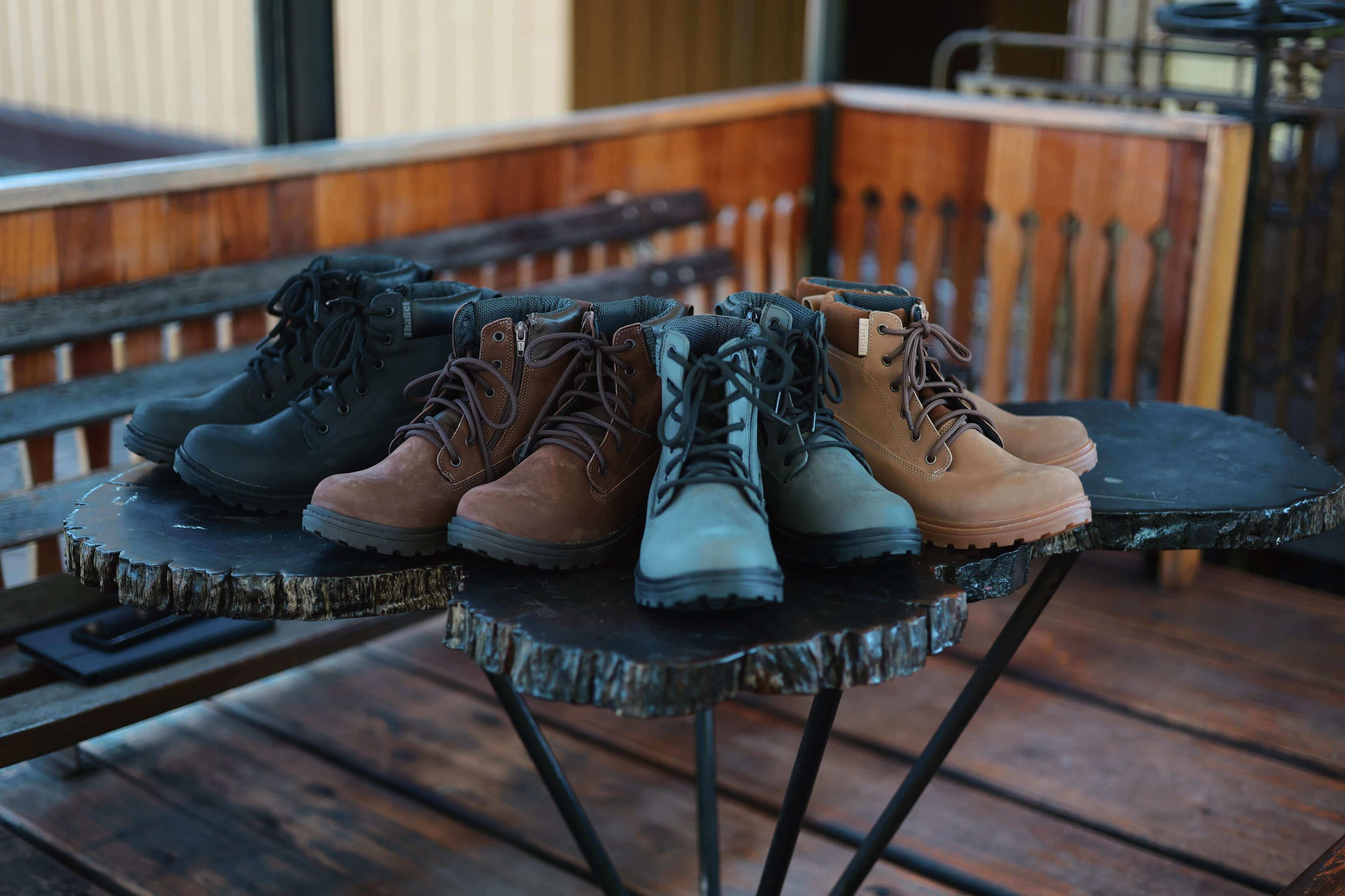 Melhores Botas para Trabalho: Conforto, Segurança e Estilo em diferentes cores dispostas sobre mesa de madeira